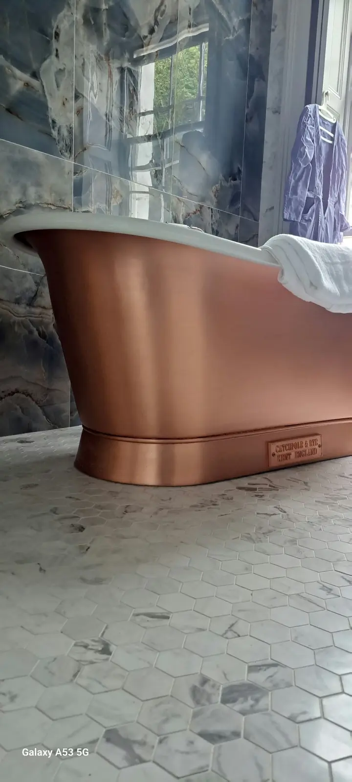Copper freestanding bath installed by Palco in a marble-finished bathroom