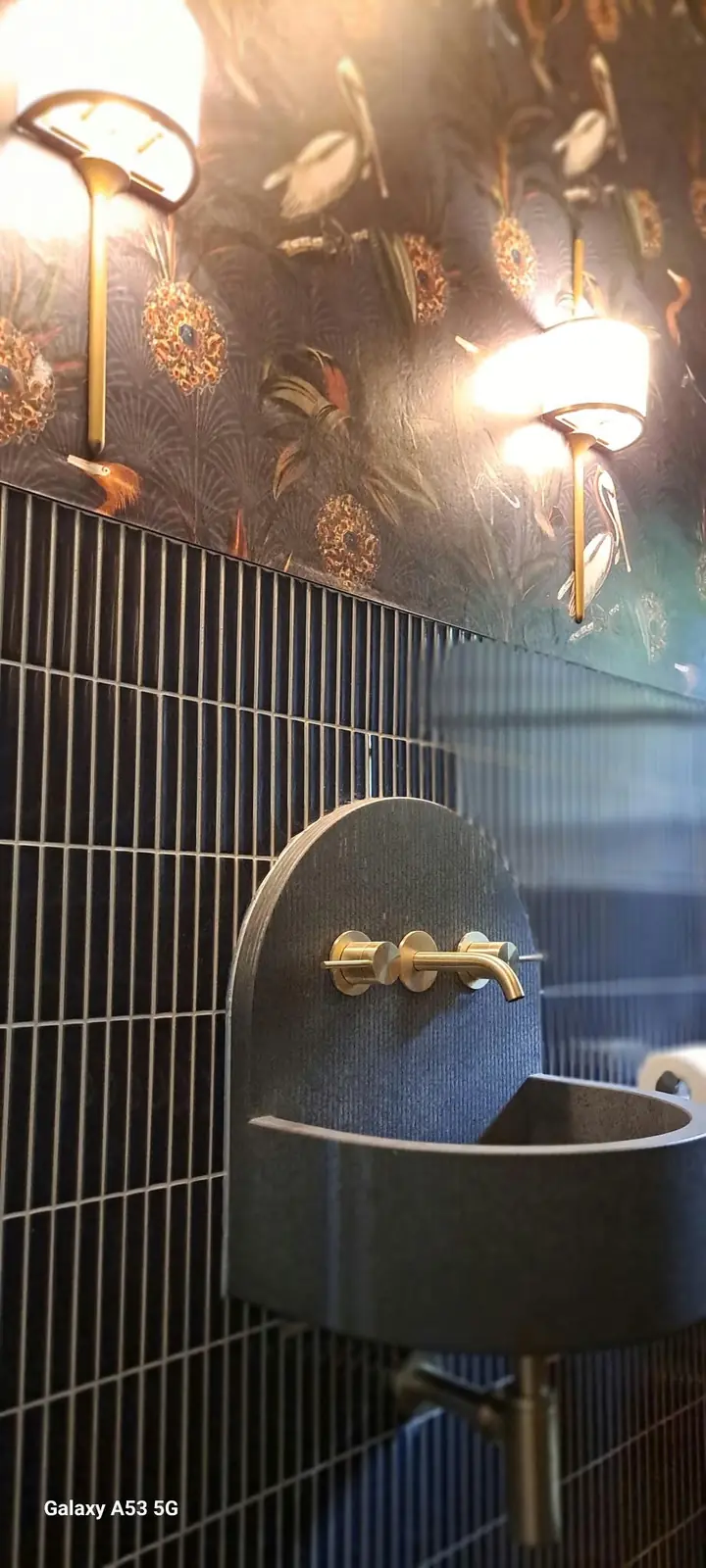 Designer wall basin, black tiling and brushed-brass fittings installed by Palco